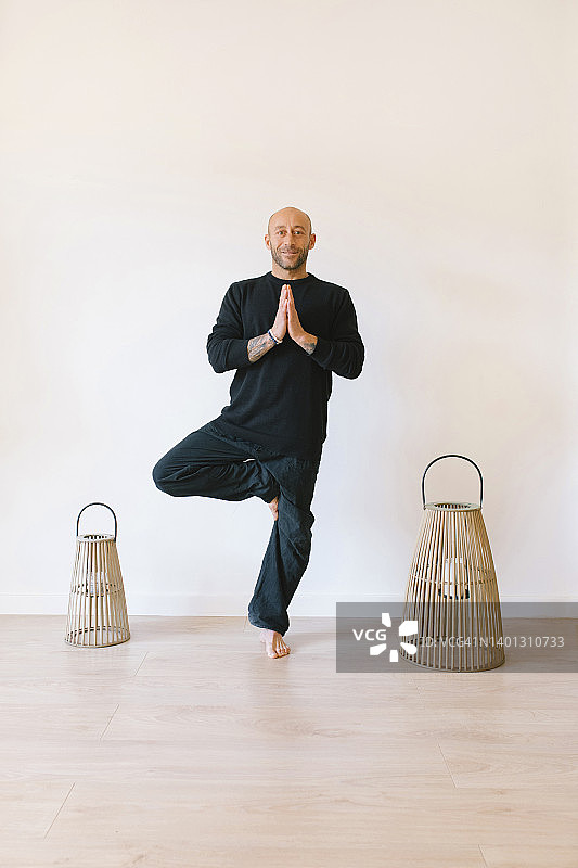 男人在瑜伽馆的墙前练习树式瑜伽图片素材