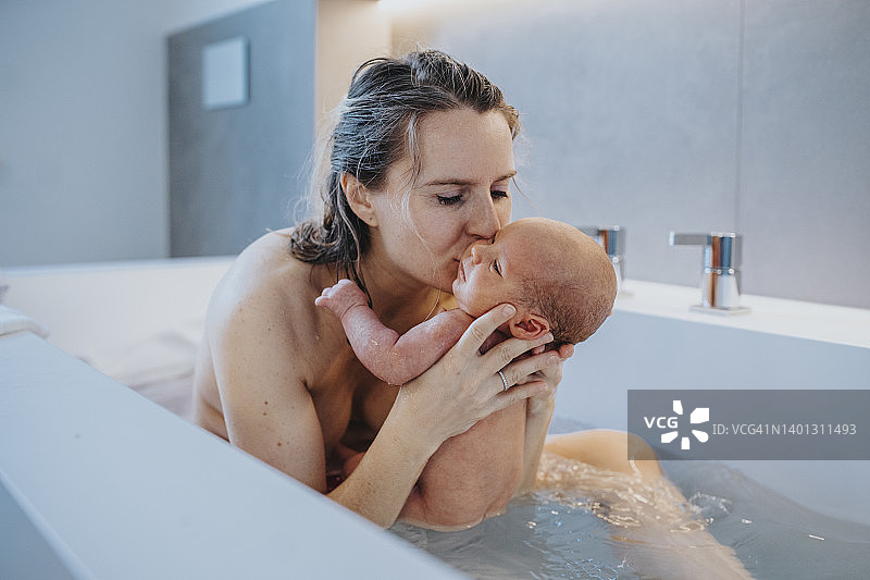 在家中，女子在浴缸里亲吻男婴图片素材