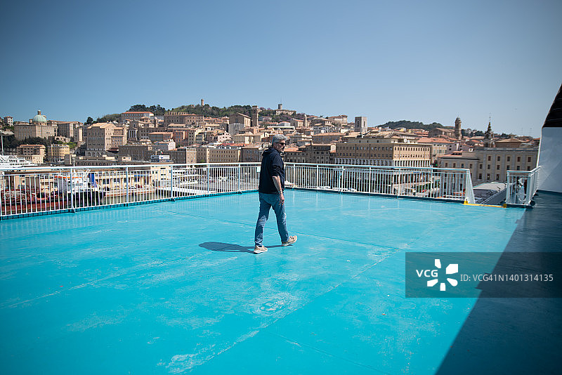 离开港口的渡轮上层甲板上的成熟男游客图片素材