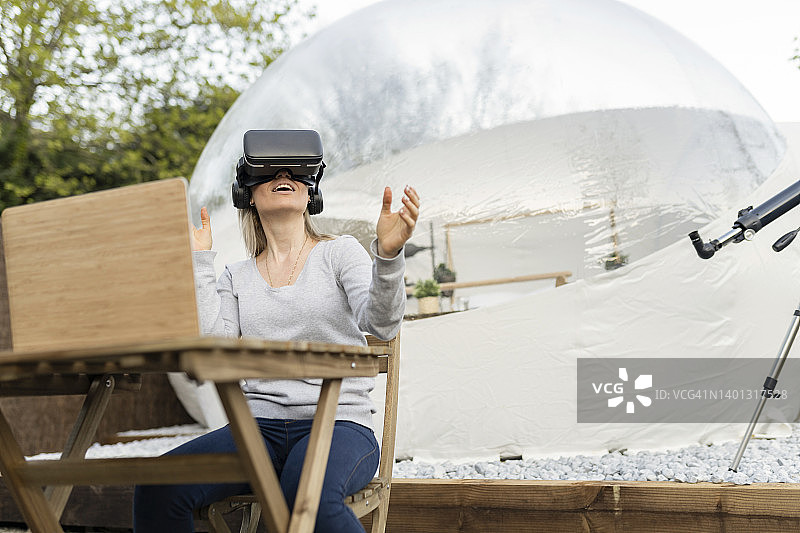 戴VR模拟器、坐着使用笔记本电脑的女人图片素材