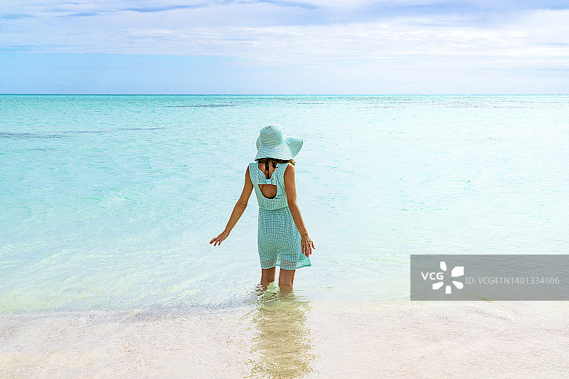 戴帽子的女人在加勒比海水晶般的海水中享受日光浴图片素材