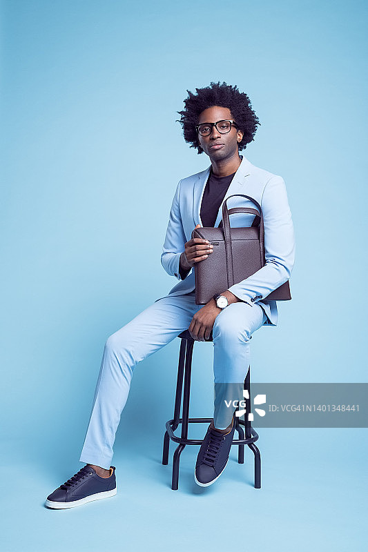 拿着公文包坐在凳子上的自信商人图片素材