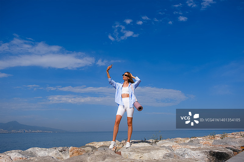 穿着运动服在海边自拍的年轻女子图片素材