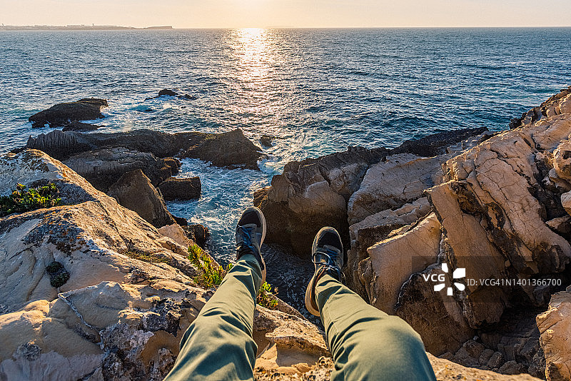 男子坐在海边悬崖边的个人视角图片素材