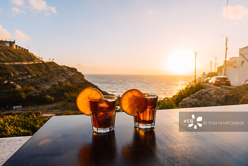 日落时分海边桌子上的两杯鸡尾酒图片素材