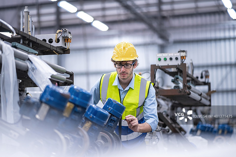 塑料制造工厂的生产线上，工程师通过平板电脑检查或维护设备图片素材