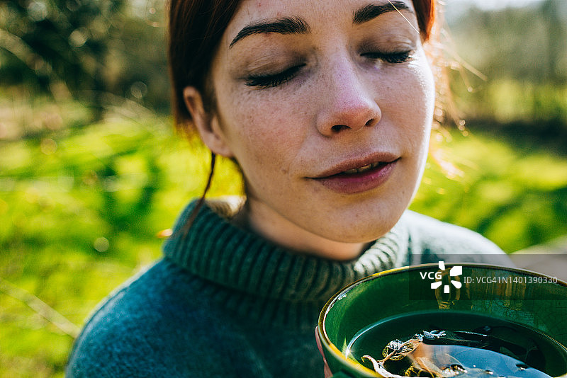 享受户外热茶的年轻红发女子图片素材