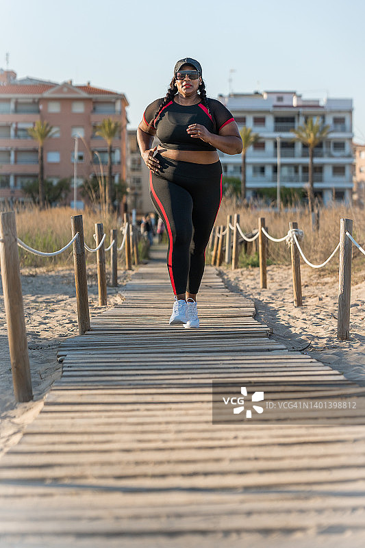 在海滩走道上奔跑的非洲裔女性正面图图片素材
