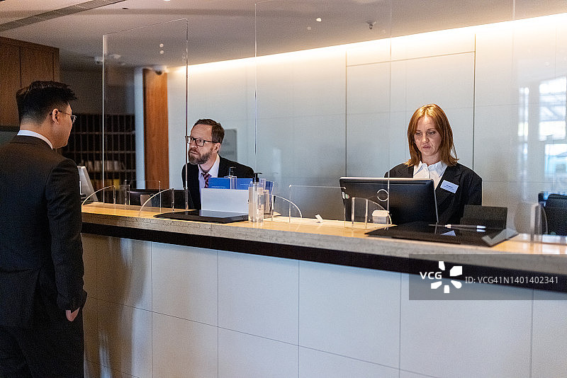酒店接待员在柜台后工作并帮助客人图片素材