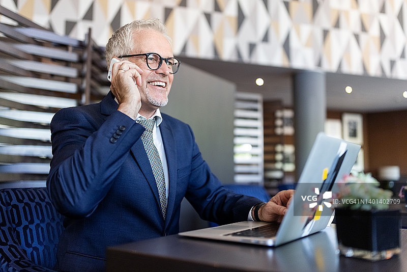 在酒店休息室打电话的快乐商人图片素材