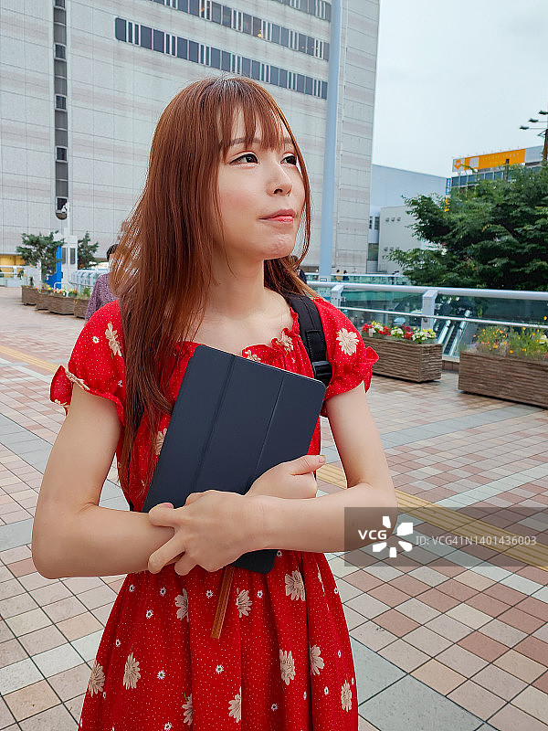 年轻女子携带平板电脑在城市中行走图片素材
