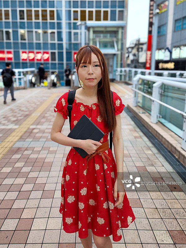 年轻女子携带平板电脑在城市中行走图片素材