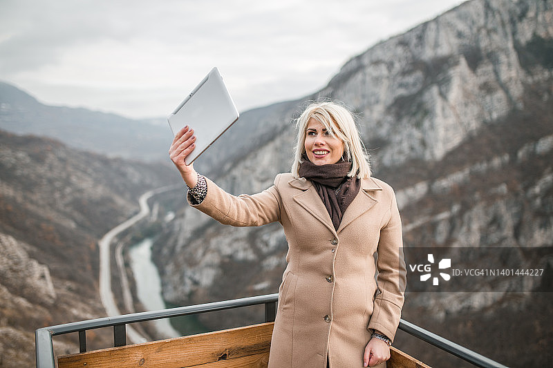微笑的女人通过视频通话向朋友展示观点的美景图片素材