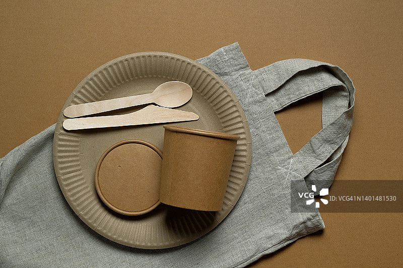 白色背景上可回收塑料和纸制成的可生物降解的一次性餐具。保护环境概念。无塑料生活。购物袋，再生材料制成的网兜。图片素材