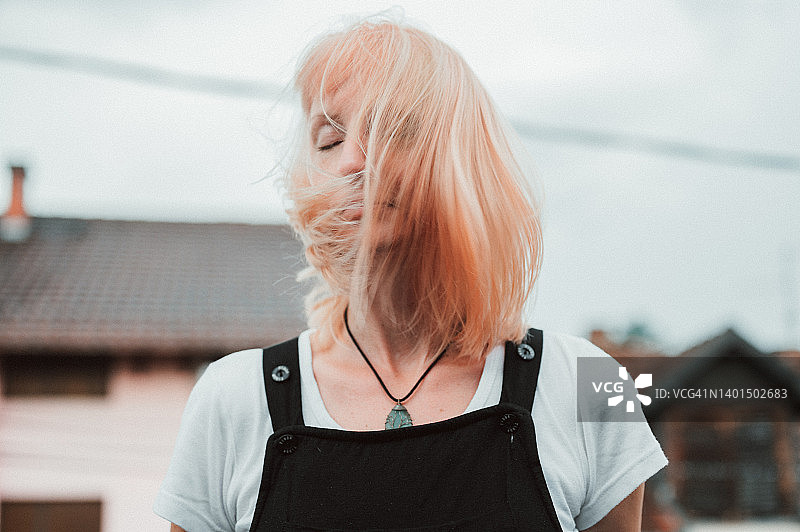 在屋顶露台上甩头发的都市年轻女人图片素材