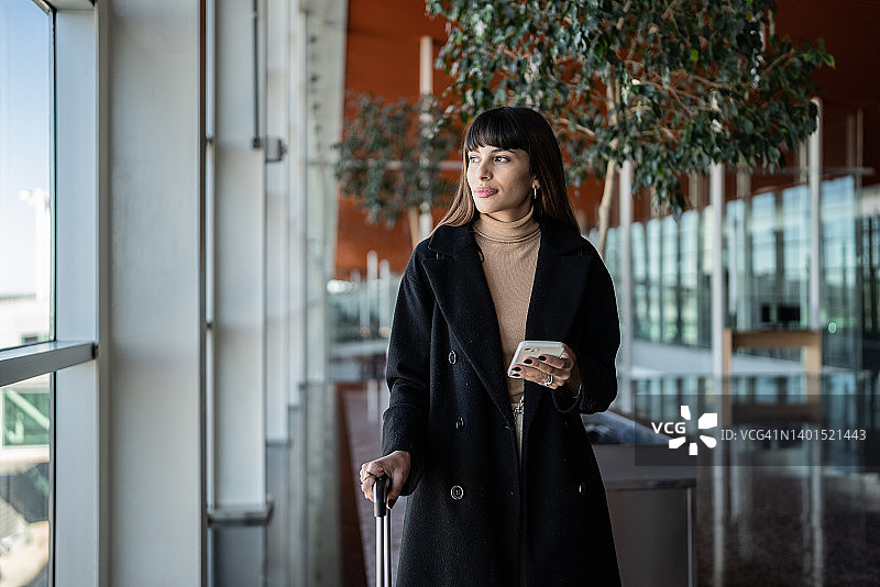 年轻女人在机场使用智能手机并沉思图片素材