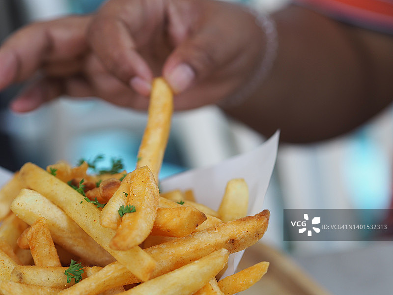 亚洲女性吃炸薯条，配番茄酱和蛋黄酱图片素材
