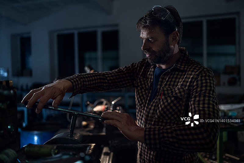 晚上在金属车间工作的年长的产业工人图片素材