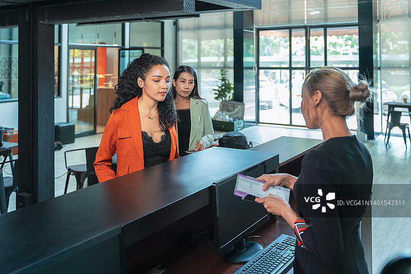 机场工作人员在办理登机手续时向商务女性递送机票图片素材