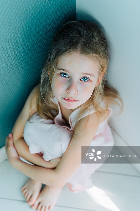 坐在角落里拥抱自己的悲伤金发小女孩图片素材