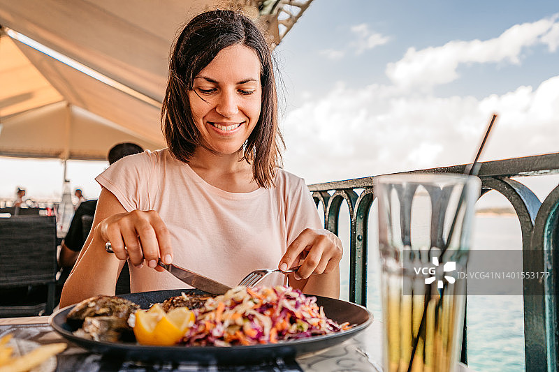 在海边享用午餐的年轻女人图片素材