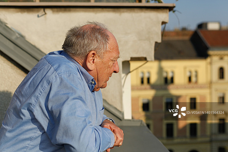在阳台上眺望城市的老年男人肖像图片素材