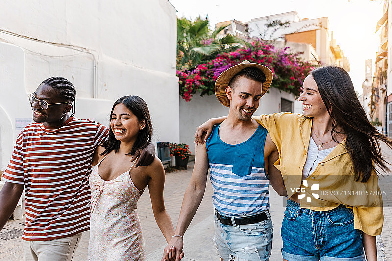在夏季假期户外一起散步时互相拥抱的快乐的各族裔游客朋友图片素材