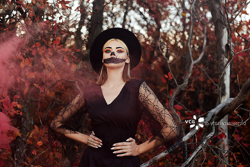 万圣节妆容的漂亮女孩肖像：秋季背景，烟雾，万圣节图片素材
