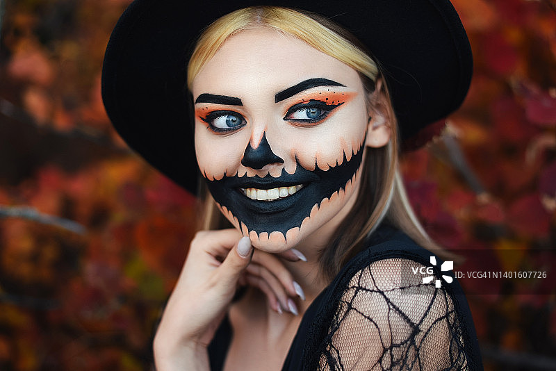 戴帽子的女孩，化着美丽的万圣节妆容，秋天的森林图片素材