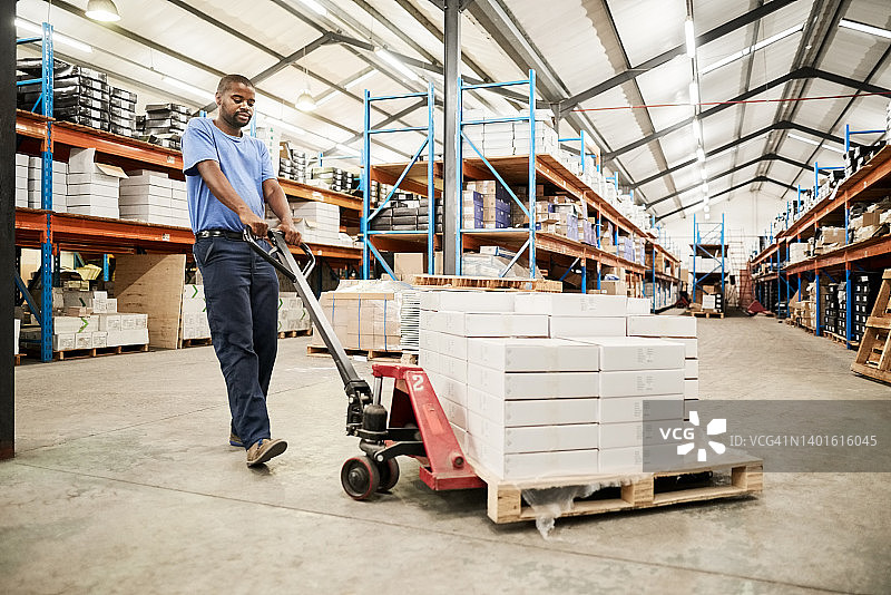 工人在仓库用托盘车移动纸箱图片素材