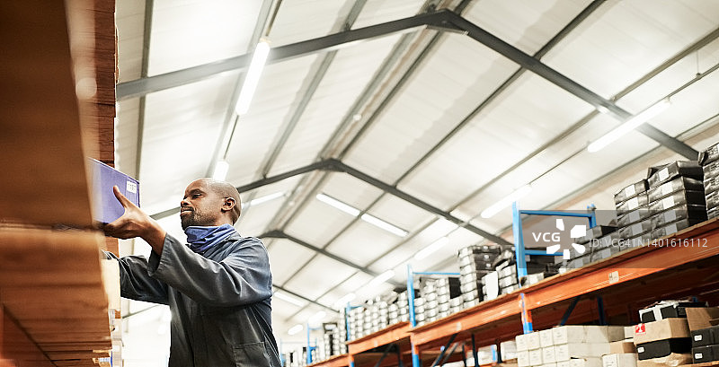 男人在大型配送仓库整理箱子图片素材