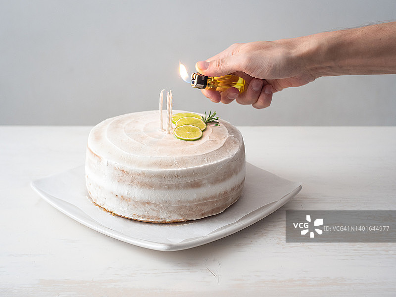 男人在白色桌子上点燃纯素生日蛋糕上的蜡烛图片素材