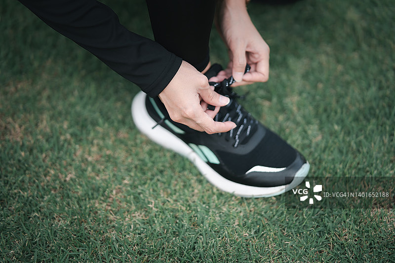 年轻的亚洲女性在公园里跪着系运动鞋带图片素材