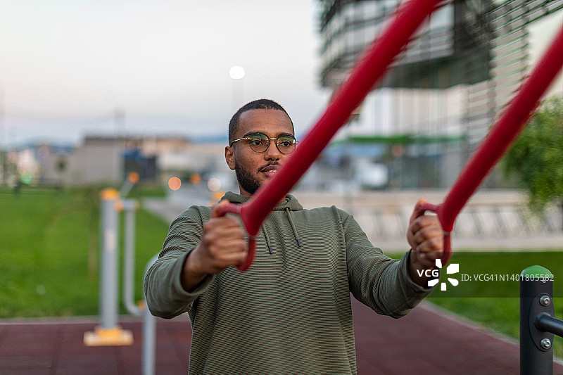 在户外健身房锻炼的年轻休闲着装男子图片素材