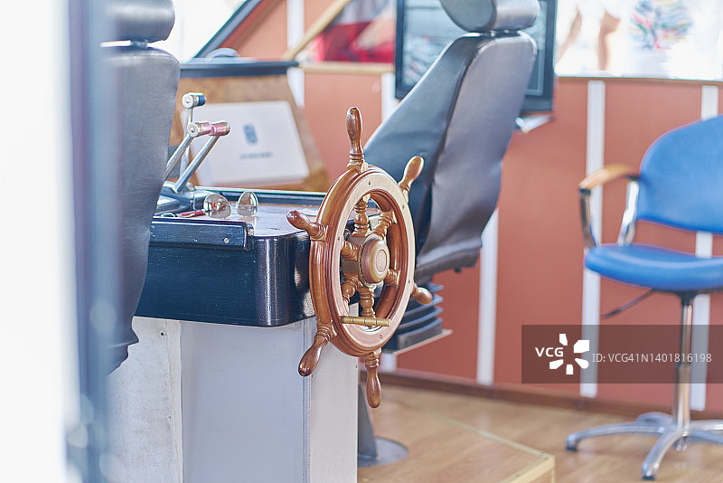 晴朗天气下航海船只控制室内的木制方向舵图片素材