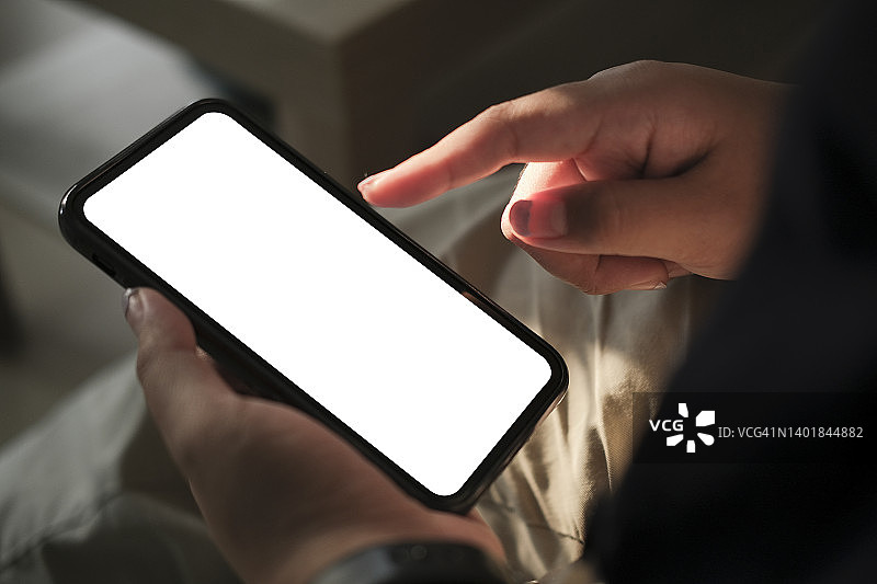 年轻女子拿着智能手机在屏幕上打字。空白屏幕，可用于输入文本信息图片素材