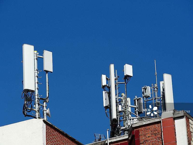 法国巴黎住宅楼顶上的移动电话天线和蓝天图片素材
