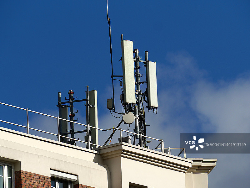 巴黎住宅楼顶的移动电话天线和多云的蓝天图片素材