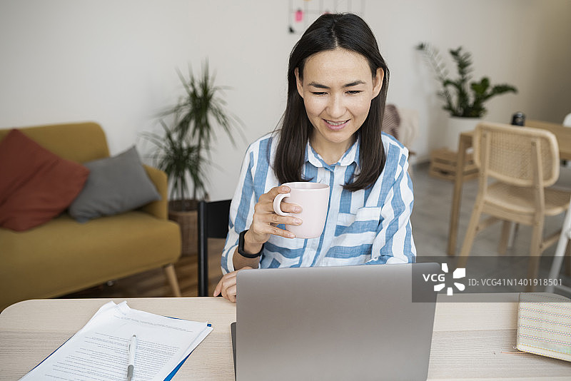 快乐的亚洲女性在家工作并享用咖啡图片素材
