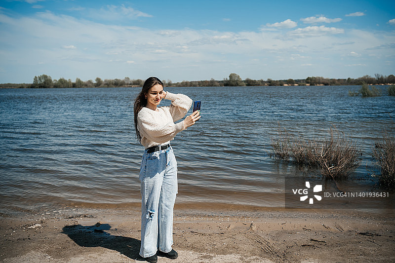 少女在河边用智能手机进行视频通话图片素材