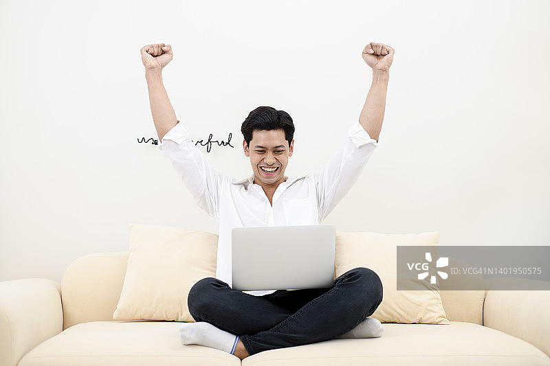 年轻男子看笔记本电脑，举起双手图片素材