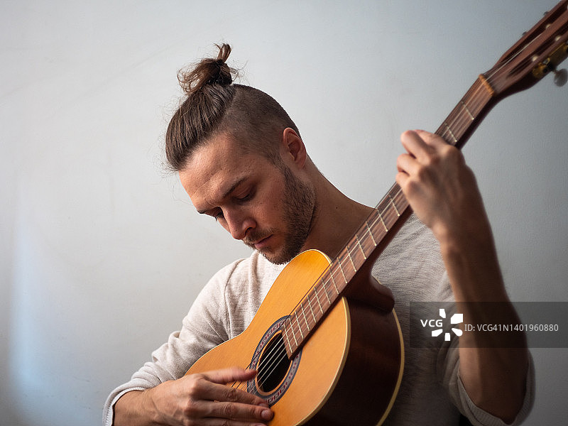 白人男人在白色背景下弹奏木吉他图片素材
