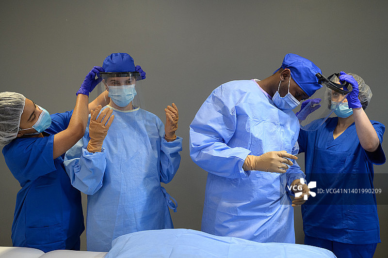 外科医生在手术助理的帮助下佩戴面罩准备手术图片素材