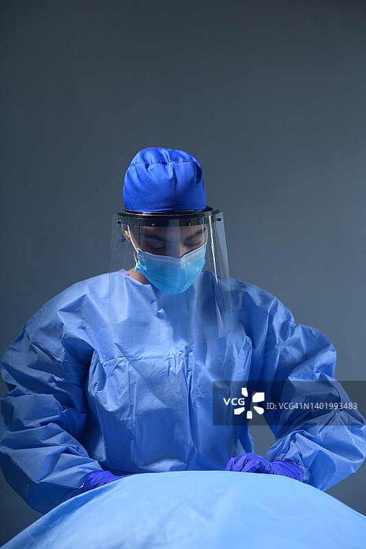 女外科医生在手术室戴着面罩和外科口罩一起做手术图片素材