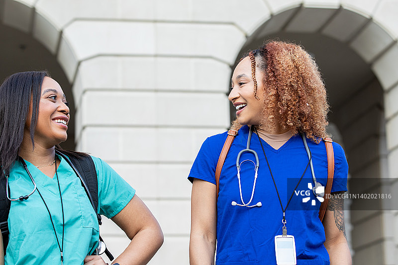 在医学院或护理学院校园里散步微笑的年轻非裔美国女性图片素材