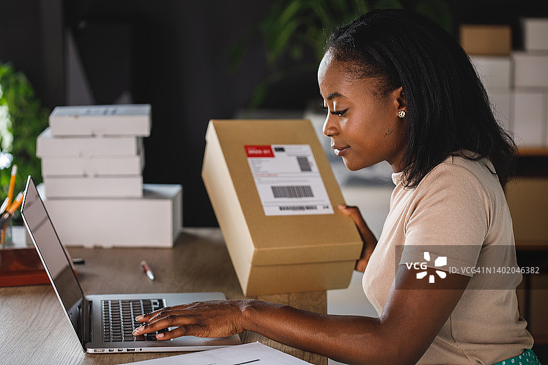 女商人用笔记本电脑输入包裹标签上的序列号图片素材
