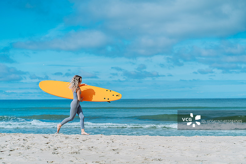 运动型女子拿着冲浪板奔向大海，准备乘风破浪图片素材