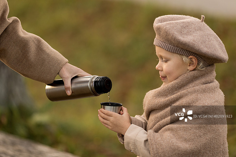 秋季，女子用保温瓶给女孩倒茶图片素材