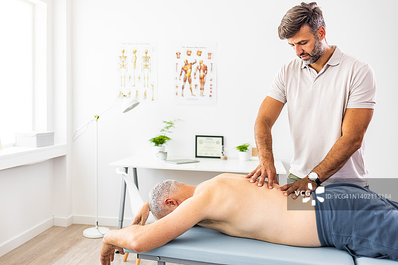 理疗师为男性运动员进行腰部运动按摩图片素材
