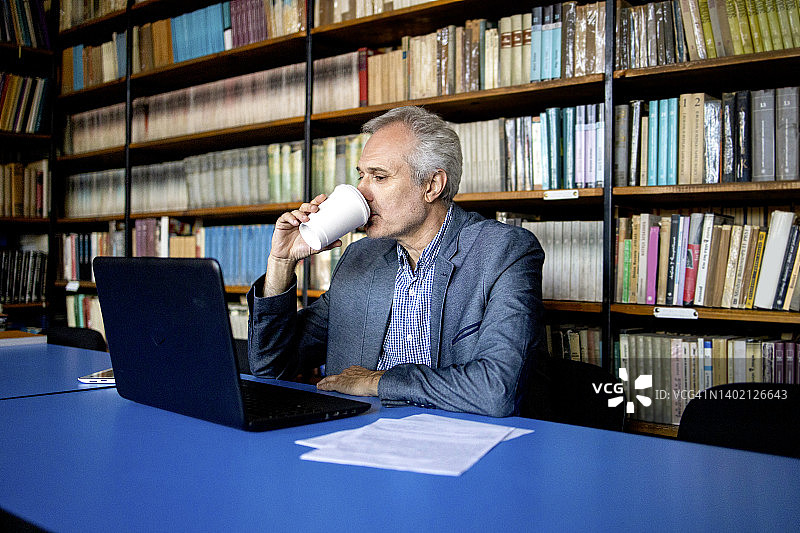 大学资深教授在图书馆查看学生统计数据图片素材